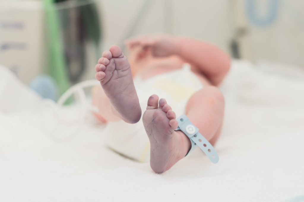 Pieds d'un nourrisson avec un bracelet en plastique bleu